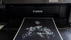 Canon printer with a high-contrast black and white map of Europe printing on glossy paper.