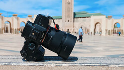 Camera with telephoto lens tilted on stone ground with mosque courtyard in background.