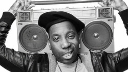 Person holding a large boombox above their head while smiling at the camera.