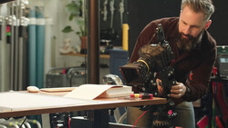 Filmmaker adjusting a cinema camera mounted on a slider in a studio workspace.