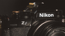 Nikon Zf mirrorless camera with attached lens, displayed against dark background with dramatic side lighting.