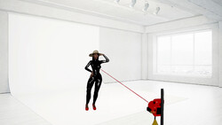 Person in black wetsuit suspended in air, connected by red line to red and yellow buoy in minimalist white studio.