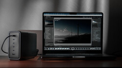 Photography editing workstation with laptop displaying RAW image in post-processing software and external power adapter.