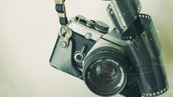 Vintage SLR camera with attached light meter and film strip arranged on neutral background.