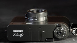 Fujifilm Xhalf rangefinder camera with mounted lens, shot from above against dark background.