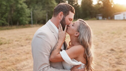 Couple embracing and about to kiss in an open field at golden hour.