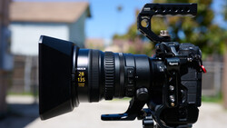 Cinema camera with anamorphic lens and matte box on outdoor set in daylight.