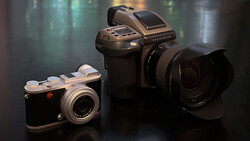 Three medium format cameras arranged on a dark surface with soft studio lighting and blurred background.