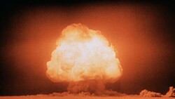 Mushroom cloud from a nuclear detonation illuminated against an orange sky at night.
