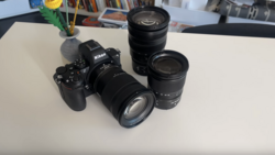 Nikon camera body with three interchangeable lenses arranged on a white surface.