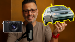 Man with microphone holds illustrations of a Sony camera and a taxi car against an orange backdrop.
