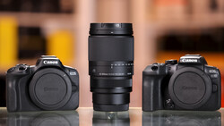 Canon EOS camera body with telephoto zoom lens flanked by two additional camera bodies on reflective surface.
