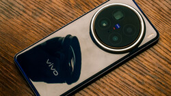 Vivo smartphone with quad camera system displayed on wooden surface, showing prominent circular camera module.
