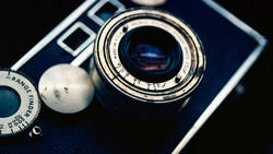 Vintage rangefinder camera with blue body and chrome lens barrel, shot from above against dark background.