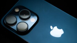 Close-up of a smartphone camera module with three large lenses and a smaller sensor, mounted on a blue device body.