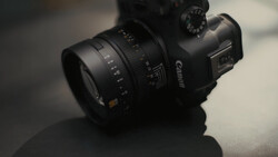Canon DSLR camera with attached telephoto lens on gray surface with soft lighting.