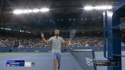 Tennis player celebrating with arms raised on indoor hard court during professional match.