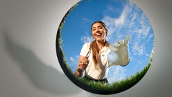 Woman in white shirt crouching in grass, framed within a circular vignette showing blue sky above.