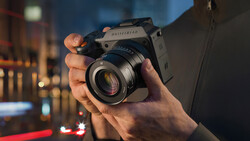 Photographer holding a medium format film camera with a prime lens against an urban nighttime backdrop.