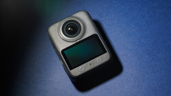 Compact dash cam with lens and small display screen on blue background.
