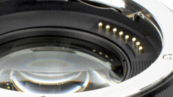 Close-up of camera lens mount showing gold electrical contacts and black metal bayonet ring.