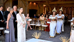 Formal event with guests in traditional Thai dress and Western formal wear in ornate wooden hall.