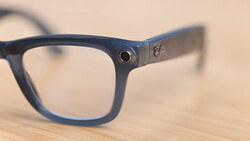 Navy blue wayfarer-style eyeglasses with clear lenses resting on a wooden surface.