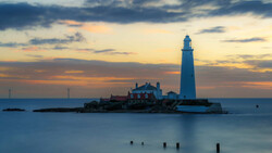 Lighthouse on rocky island at twilight with long exposure water effect.
