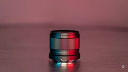 Camera lens with blue and red gel lighting against a pink background.