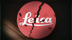 Graphic design featuring the Leica logo with a jagged crack running through a red circular background.
