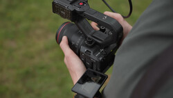 Videographer holding a professional cinema camera with external monitor mounted on top.