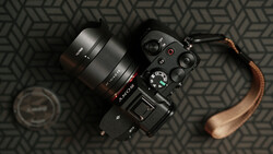Sony mirrorless camera with attached lens and brown leather strap on geometric patterned surface.