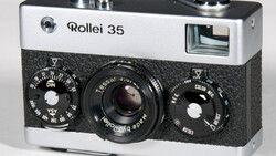 Rollei 35 compact film camera with white and black body, showing dual control dials and Tessar lens.