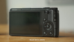 Ricoh GR IV compact digital camera displayed from the rear on a wooden surface.