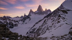 Snow-covered peaks at sunrise with jagged granite spires rising above an alpine glacier.