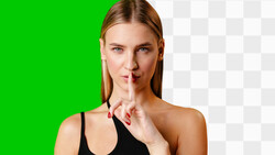 Woman with reddish-blonde hair making a shushing gesture with her finger to her lips.