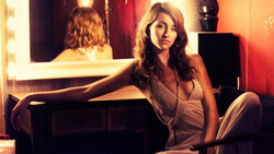Woman at vanity mirror with warm golden lighting and red backdrop.