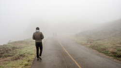 Runner jogging solo on a misty mountain road with yellow center line.