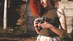 Person holding a vintage rangefinder camera in golden hour sunlight.