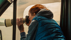 Person photographing through a car window with a telephoto lens.
