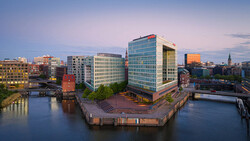 Modern waterfront cityscape at dusk with contemporary office buildings surrounding a central canal basin.