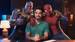 Man in green polo posing with costumed characters in studio lighting setup.