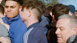 Group of young men gathered outdoors in casual clothing during daytime.