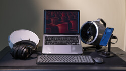 Creative workspace setup with laptop, headphones, microphone, keyboard, and phone on dark desk.