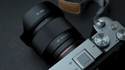 Mirrorless camera with wide-angle lens mounted, showing manual focus ring and aperture markings.