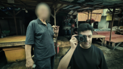 Young photographer holding a vintage film camera in an industrial workshop setting.