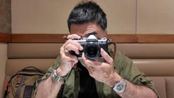Photographer holding a rangefinder camera up to his face to compose a shot.