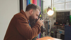 Photographer looking through camera viewfinder in studio with professional lighting setup.