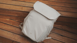 White camera backpack viewed from above on a wooden floor, showing padded compartments and straps.