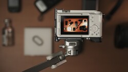 Compact camera mounted on a tripod displaying an overhead flat lay composition on its rear screen.